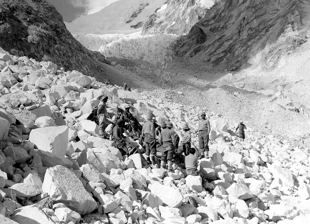İngiliz Everest Seferi, Albay John Hunt’ın liderliğinde düzenlendi. Başarıya ulaşmak için yalnızca iki güçlü dağcıya sahip olmak yeterli değildi. Çok sayıda dağcı, Şerpa, taşıyıcı ve destek personelinin katıldığı kapsamlı bir organizasyon gerekiyordu.

Ekipmanlar, yiyecekler, çadırlar, oksijen tüpleri ve tırmanış malzemeleri dağın yüksek kesimlerine taşındı. Yüzlerce taşıyıcının emeğiyle oluşturulan kamplar, zirveye ulaşma girişiminin temelini oluşturdu.